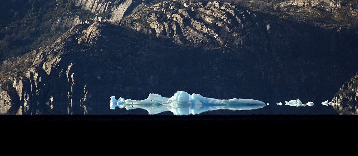 An iceberg mirrored in glacial water in Torres del Paine, as seen from the paid Lago Grey catamaran