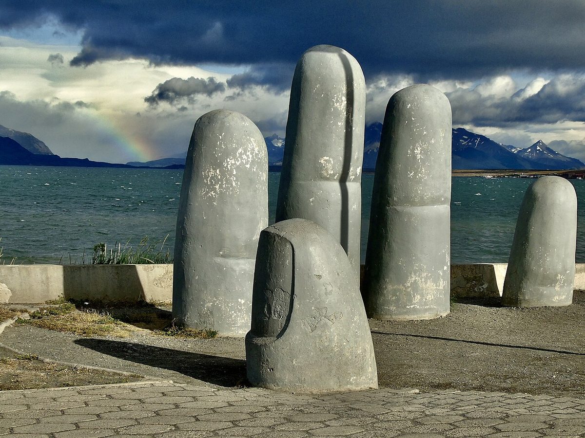 La Mano, the concrete hand sculpture on the waterfront of Puerto Natales, with the channel and mountains behind