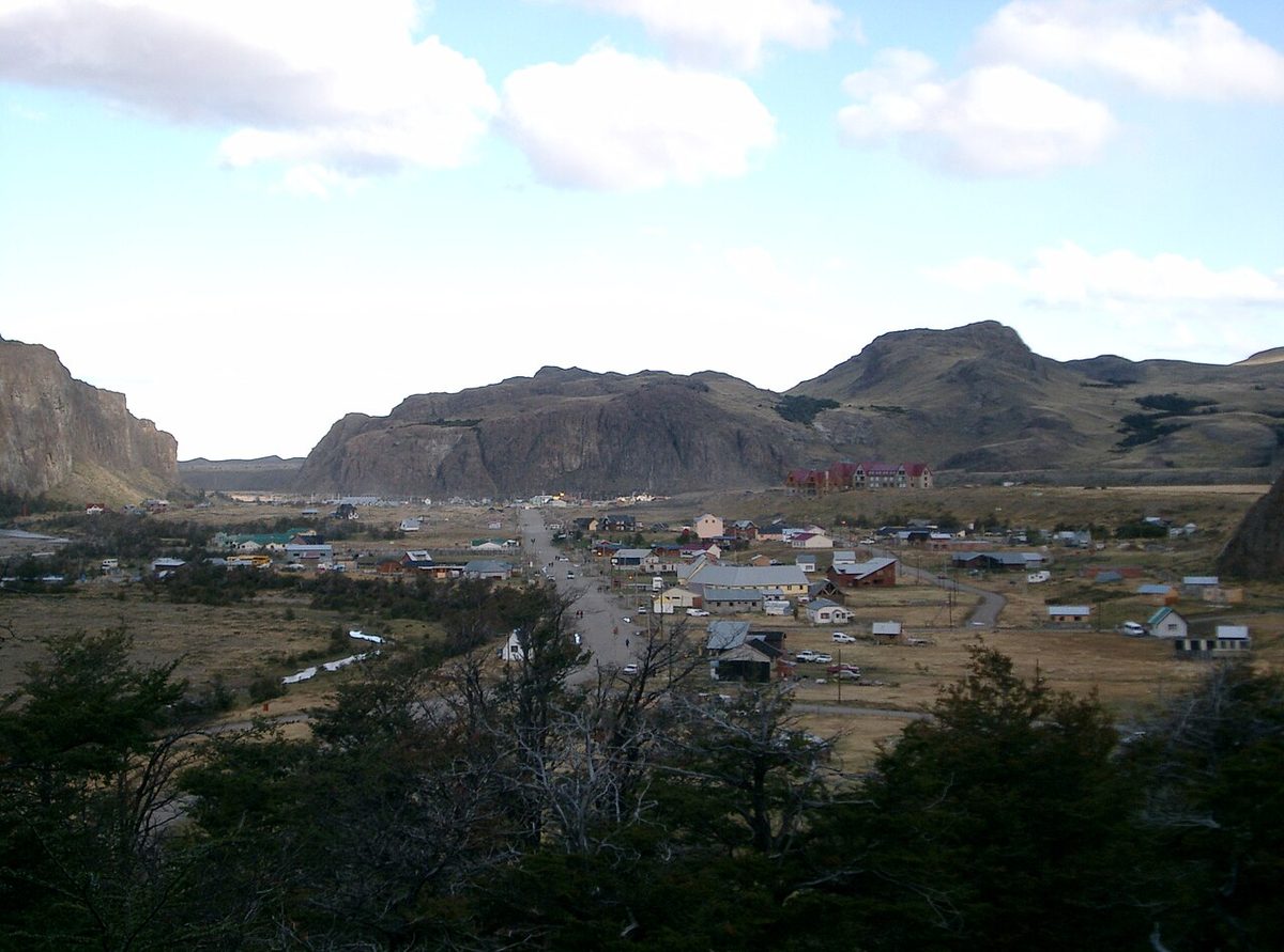 A street of low houses, inns and shops in El Chaltén with mountains rising behind the town