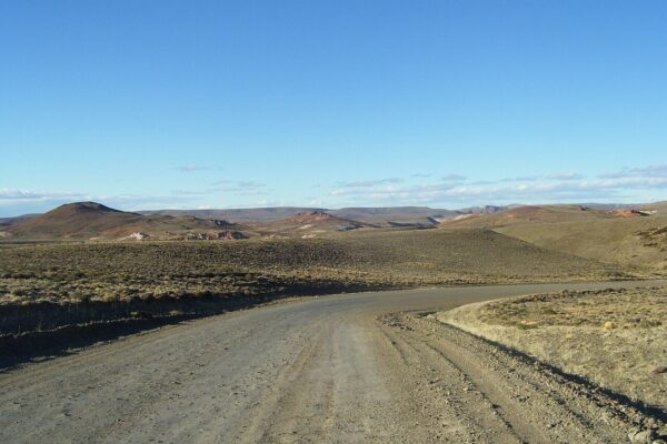A gravel stretch of Ruta 40 curving across the dry steppe of Santa Cruz province under a clear sky