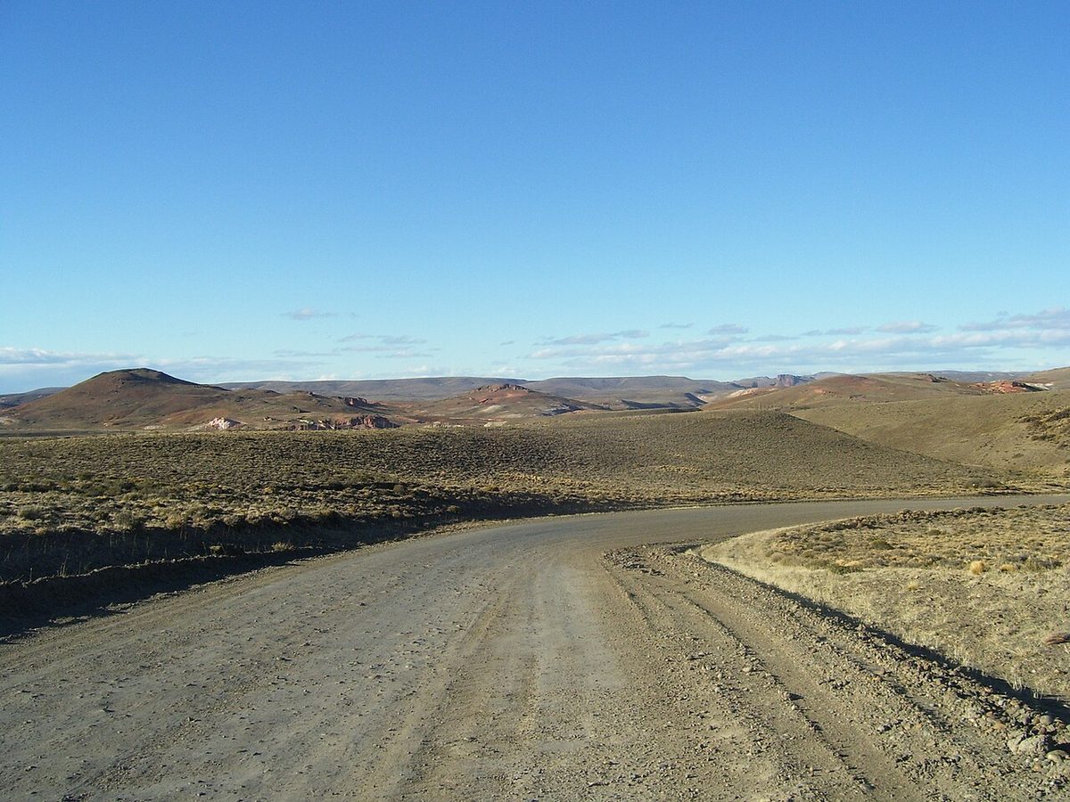 A gravel stretch of Ruta 40 curving across the dry steppe of Santa Cruz province under a clear sky