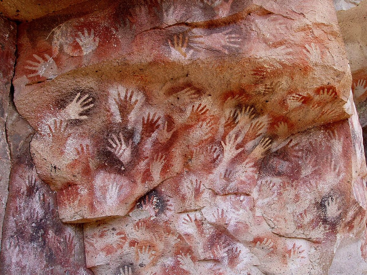 Stencilled hand paintings in red, white and black on the rock wall at Cueva de las Manos in the Río Pinturas canyon