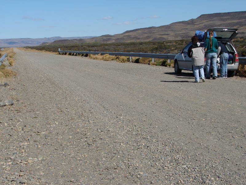 Travellers stopped beside their car on the gravel of Ruta 40 near Lago Cardiel in Santa Cruz