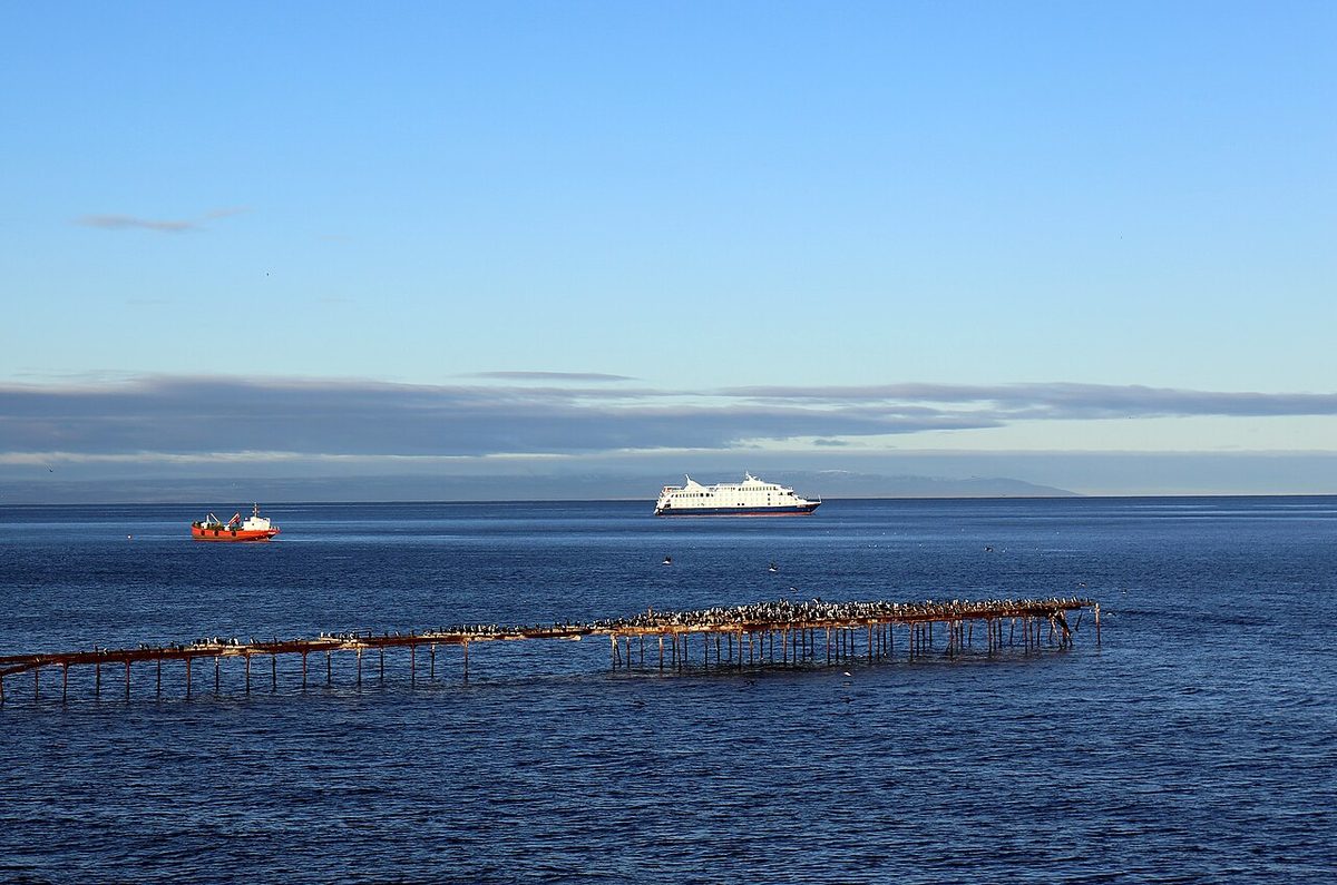 Ships on the Strait of Magellan seen from the Punta Arenas waterfront, with an old pier in the foreground